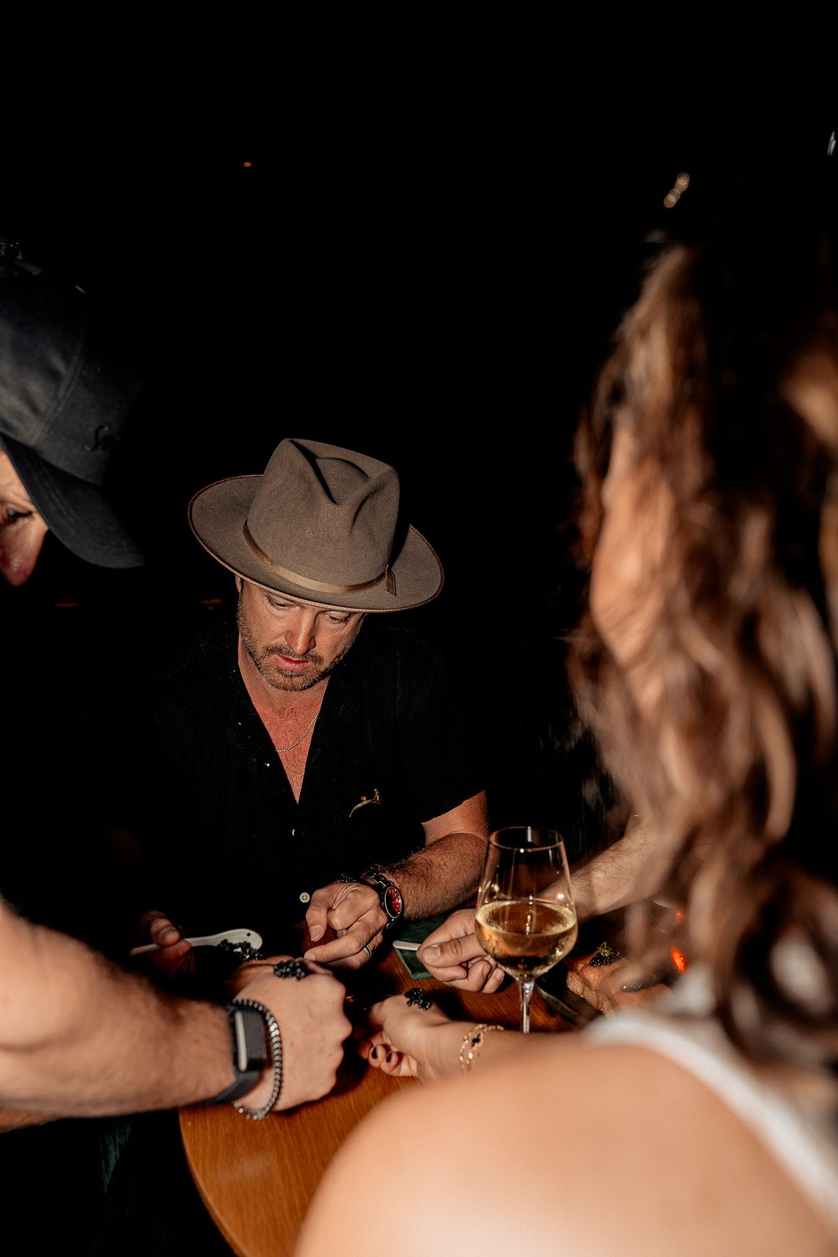 Aaron Paul seated at a low-lit dinner table with guests