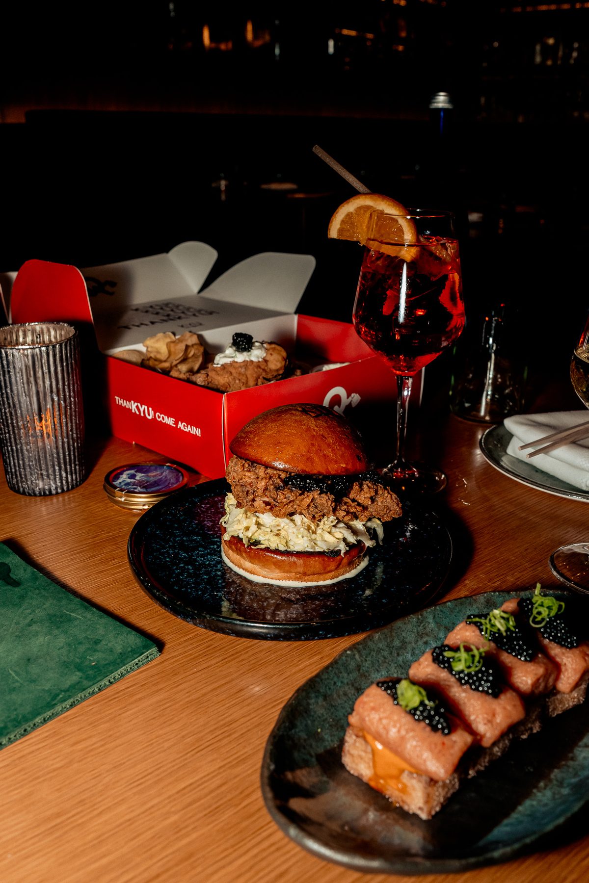 The chicken sandwich, the ThanKYU box and a plate of salmon with a cocktail